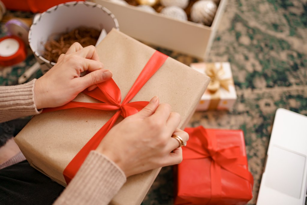 close-up-female-hands-tying-a-red-ribbon-bow-on-a-craft-gift-box.jpg